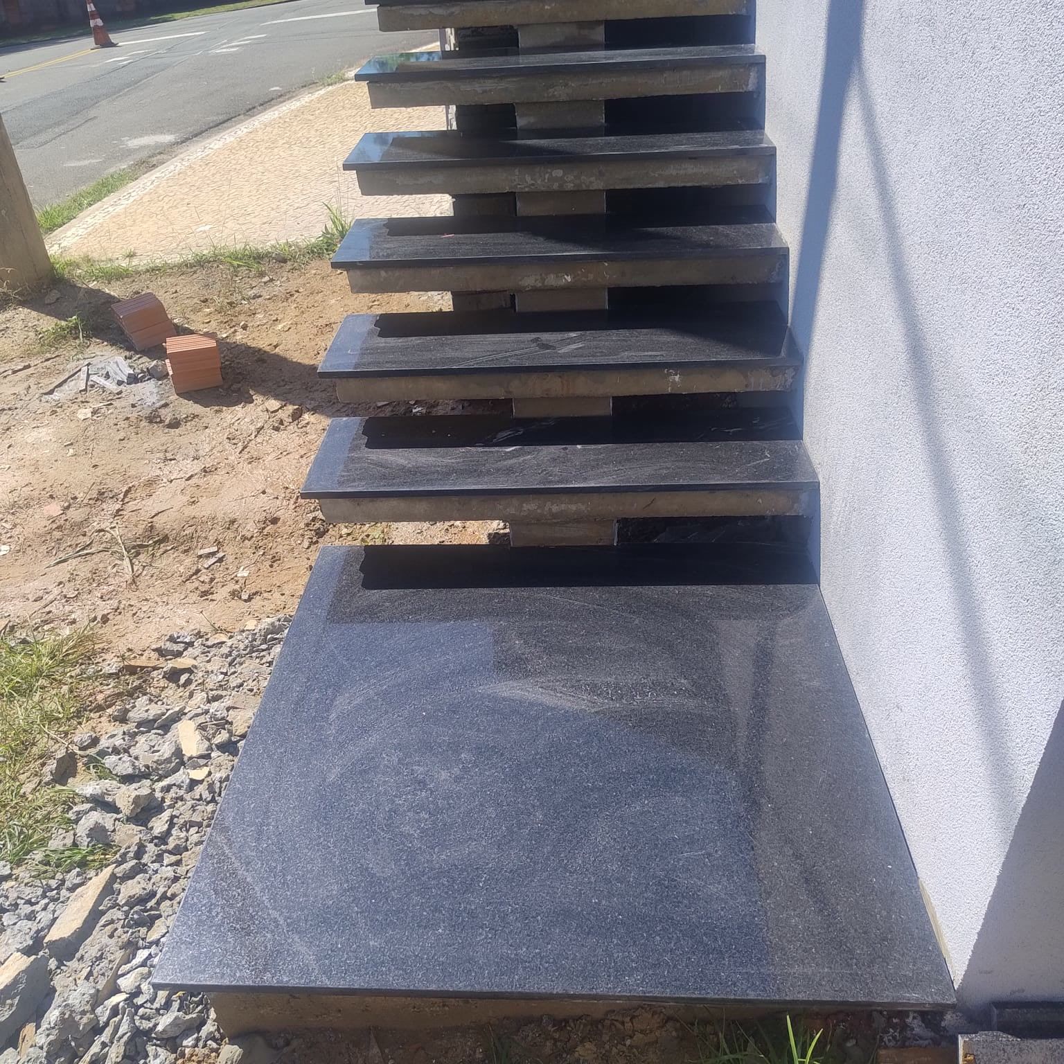Degraus de granito preto saindo da parede, em balanço