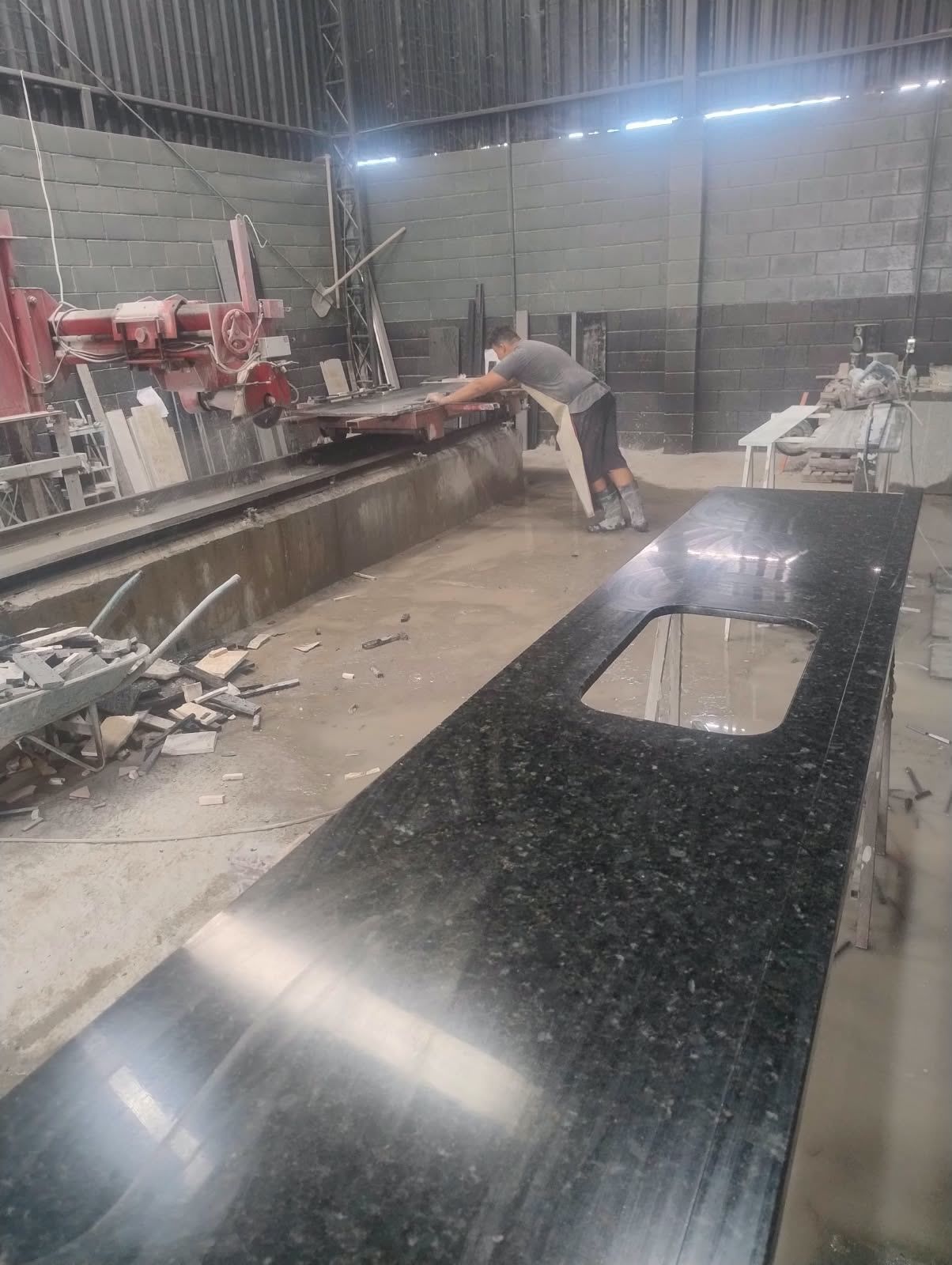 Operador na máquina de corte da oficina, com uma bancada pronta em primeiro plano