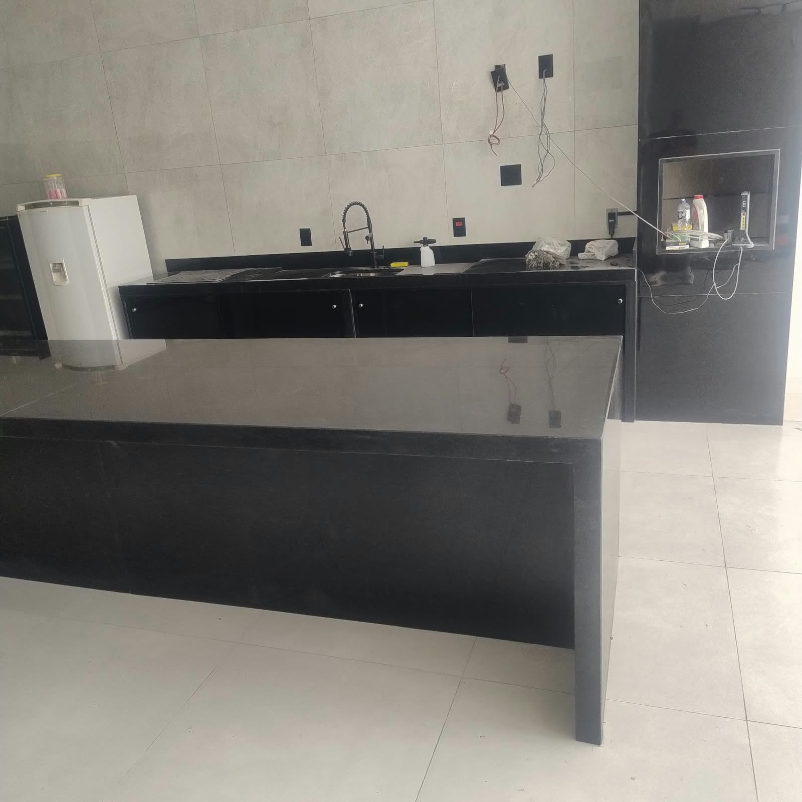 Churrasqueira revestida de granito preto, com bancada de apoio